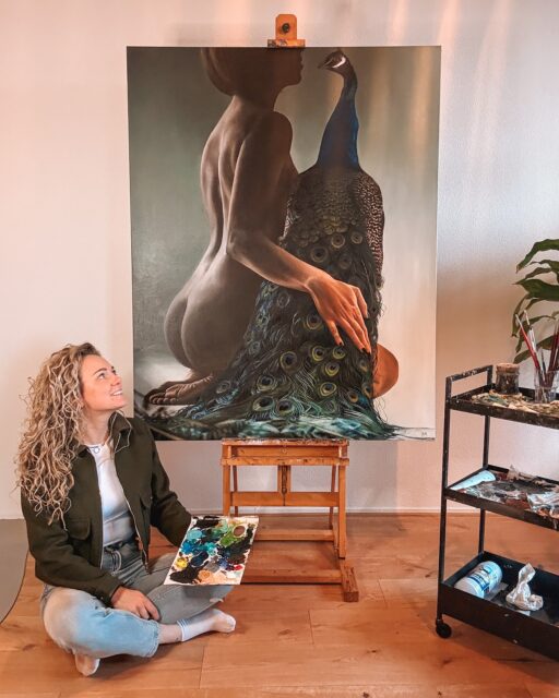 Het eindresultaat! 🦚✨

En dit is ‘m dan.

Proud Marie.

En ja… ik ben écht trots. Trots als een pauw! Hahah

Wat een proces is dit geweest. Zóveel uren. Zóveel lagen. Pfoe en die veren… die hebben me echt even laten zweten. Ik had nog nooit eerder zo’n pauw geschilderd. Al die structuren. Al die kleurovergangen. Elk “oogje” in de veren moest kloppen. Het mocht niet te druk worden, maar ook de diepte niet verliezen. 

Er zijn momenten geweest dat ik dacht: waar ben ik aan begonnen?

Maar nu ik haar zo zie staan… alles samen… dan weet ik weer waarom.

Het contrast tussen de zachte huid en die krachtige pauw. De houding. De rust. De intensiteit. Het klopt.

En het leuke is: ik mag haar van de klant meenemen naar de beurs op 15, 16 en 17 mei. Daar hangt ze straks in het echt. En geloof me… in het echt is ze nog indrukwekkender dan op een foto!

Dus als je nieuwsgierig bent naar alle details van dichtbij, kom vooral langs. Ik vertel je er met alle liefde meer over.

Proud Marie.

Eindelijk helemaal af. En ik ben er zo blij mee. ✨

p.s. Ik mag vrijkaartjes weggeven voor het event! Schrijf je in voor mijn nieuwsbrief via de link in mijn bio en maak kans op 2 tickets! 🔥

—
Wie ben ik?
Emily van de Wiel

Ik ben kunstenares, gespecialiseerd in hyperrealistische schilderijen die vrouwelijke kracht en kwetsbaarheid vangen. Mijn werk draait om detail, licht en intimiteit. Vaak persoonlijk, soms rauw, maar altijd echt. Ik maak zowel vrij werk als schilderijen in opdracht, ieder doek met liefde en precisie geschilderd.

Laten we connecten!